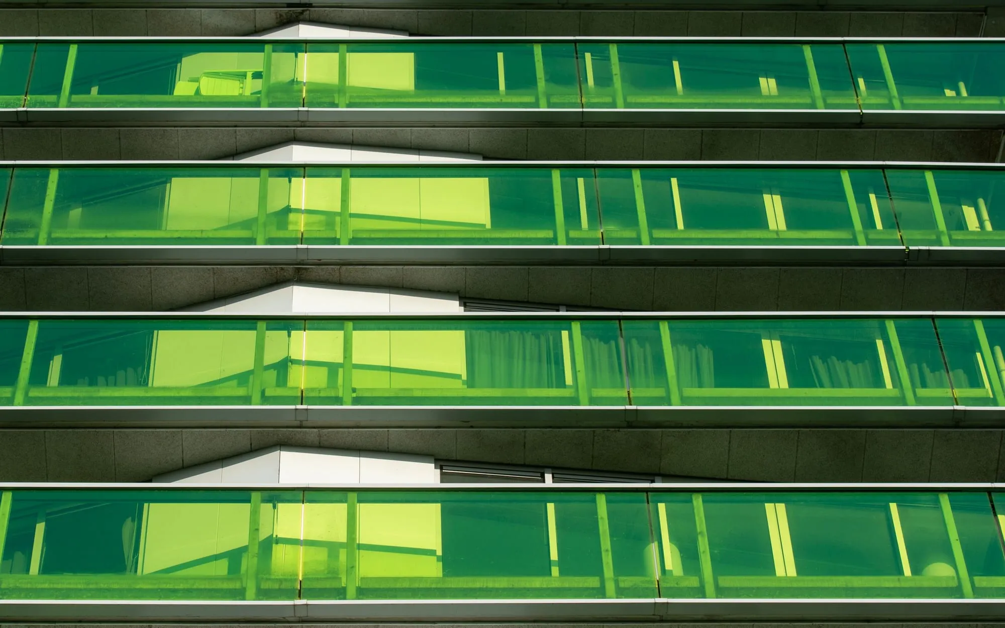 Rows of green glass balconies on a modern building