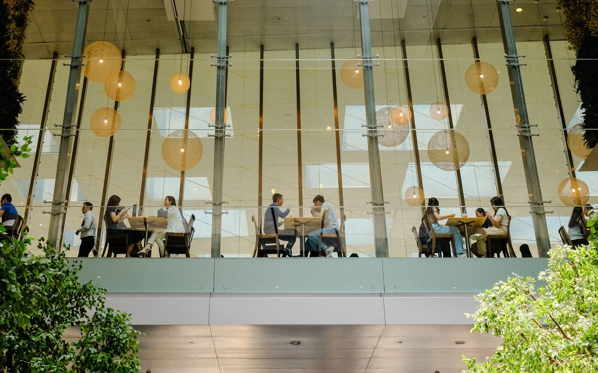 A bright office atrium under a large glass skylight, with people working below