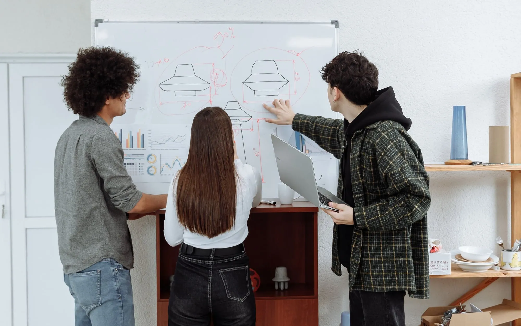 Three colleagues sketching ideas on a whiteboard in a bright office