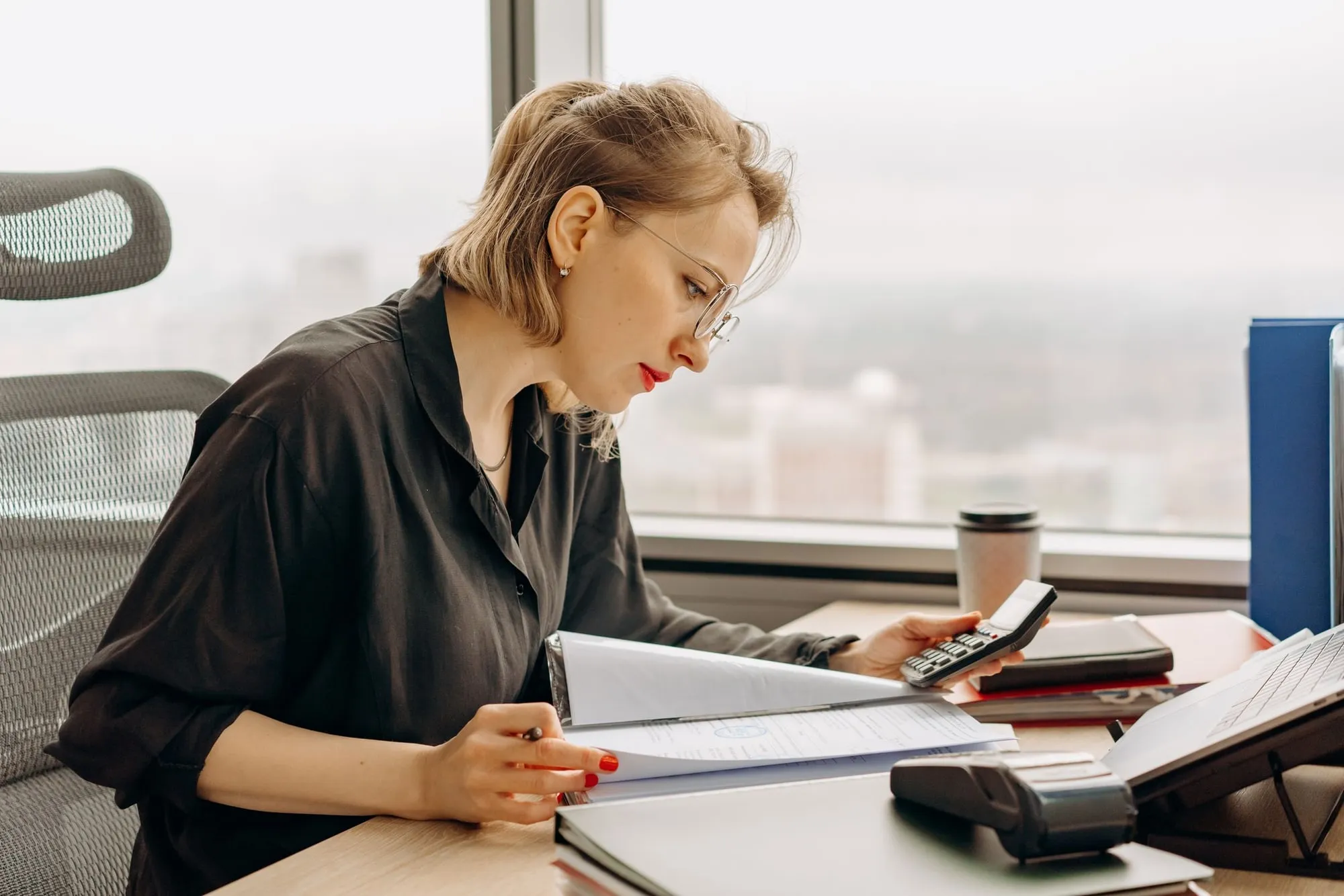 A woman working through financial documents with a calculator