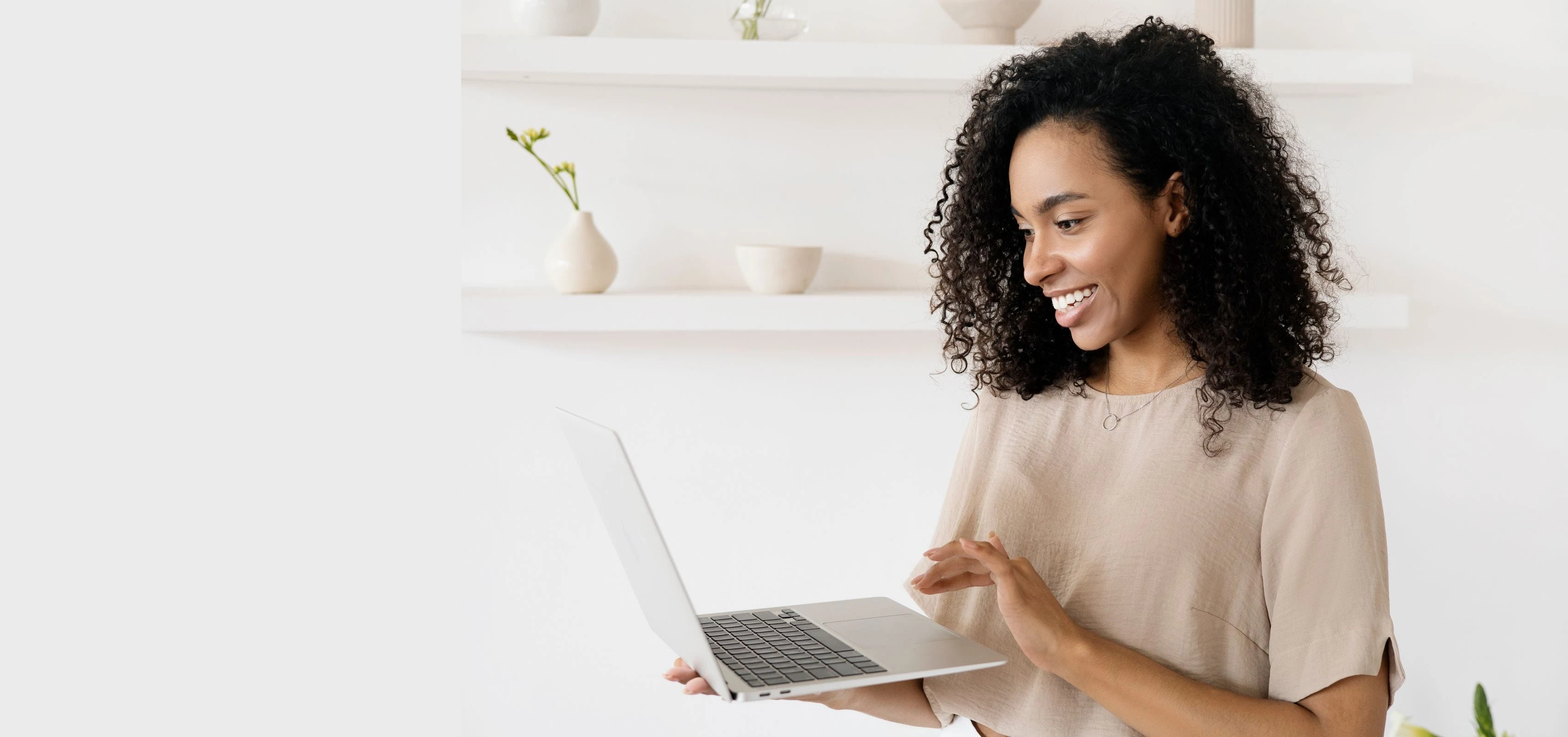 A woman smiling at her laptop in a bright room