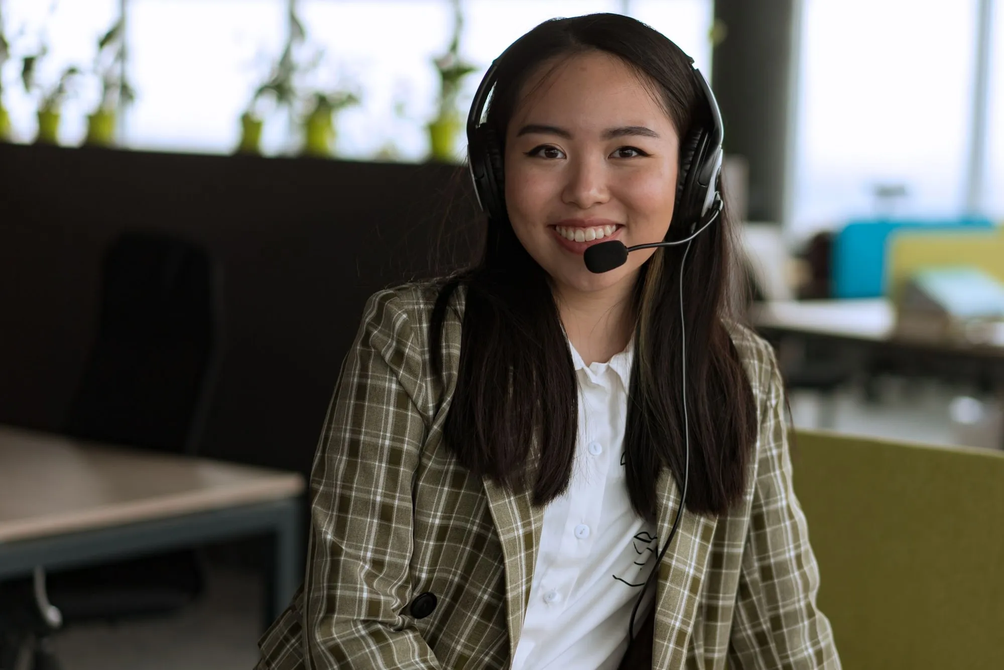 A support agent with a headset smiling at her desk